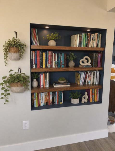 FORM & FUNCTIONAL DECOR— A small hallway pass-through was thoughtfully transformed into a custom book display making purposeful use of limited space for a book-loving couple in an intimate in-law apartment.